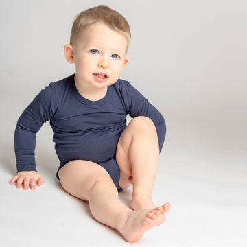 Mosolygó kisfiú játszik LiaaBébé Hosszú Ujjú Bodyban, navy blue színben.